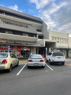 three cars parked in front of a building on a street with no parking spaces around them