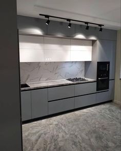 an empty kitchen with white cabinets and marble counter tops