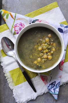 a white bowl filled with soup on top of a table next to a spoon and napkin