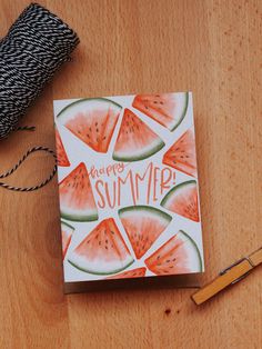 a watermelon card sitting on top of a wooden table next to a spool of twine