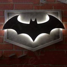 the batman symbol is lit up on a brick wall