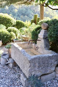 a stone fountain surrounded by rocks and plants