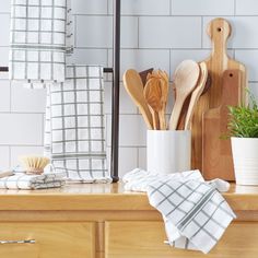 kitchen utensils and wooden spoons are sitting on the counter next to a potted plant