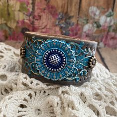 v'¯) .`*.¸.*' ❤ CONCHO COLLECTION ❤ ¸.*'.*'¨) ¸. (¸.*'(¸.*' (¸. Hand Painted Leather My leather concho cuff bracelets will add a rustic feminine touch to your look! Each made from tooled leathers & beautifully detailed conchos. Filigrees and rivets add dimension. They can be dressed up or down to compliment any outfit. Buy it ---- Wear It----Make it your own! This DESIGN ~ ❤ Silver flower concho inked in shades of blue; cobalt and deep turquoise patina. ❤ Gorgeous tooled leather, painted bro Bohemian Adjustable Flower Cuff Bracelet, Adjustable Bohemian Flower Cuff Bracelet, Blue Sunflower, Jewelry Rustic, Jewelry Making Business, Deep Turquoise, Bracelet Summer, Leather Wristband, Bracelet Flower