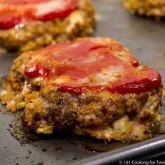 hamburger patties with ketchup and cheese on a baking sheet