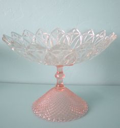 a pink glass bowl sitting on top of a white table next to a blue wall