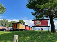 a red and yellow train traveling past a sign