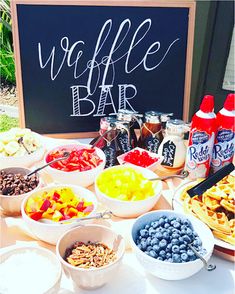 a table topped with lots of different types of food next to a chalkboard sign