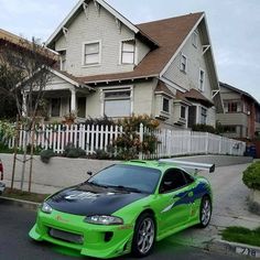 a green sports car parked in front of a house