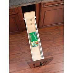 an open drawer in the middle of a kitchen with wood flooring and granite counter tops