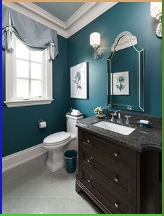 a bathroom with blue walls and white fixtures, including a sink, toilet, and mirror