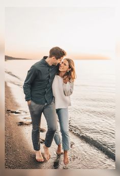 an engaged couple walking along the beach at sunset