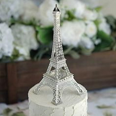 a white cake with the eiffel tower on top is sitting in front of flowers