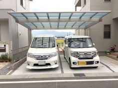 two white cars parked in front of a building with an awning over the top