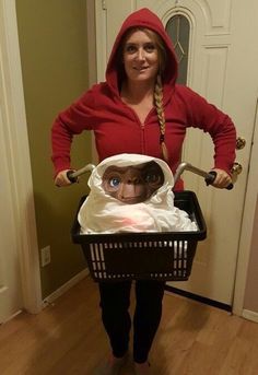 a woman in a red hoodie is holding a basket with an image of a baby in it