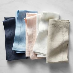 five folded napkins in different colors on a white surface