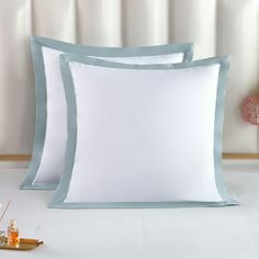 two white and blue pillows sitting on top of a bed