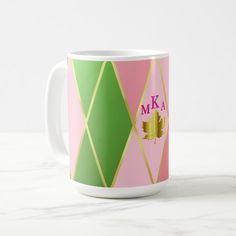 a pink, green and gold coffee mug with the letter k on it