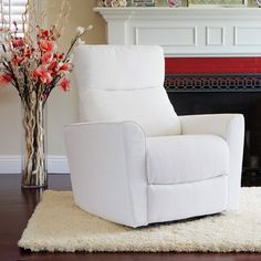 a white recliner sitting on top of a rug in front of a fire place