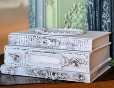 two white boxes sitting on top of a wooden table next to bookshelves with ornate designs