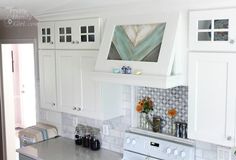 a kitchen with white cabinets and stainless steel stove top oven in the center, surrounded by flowers