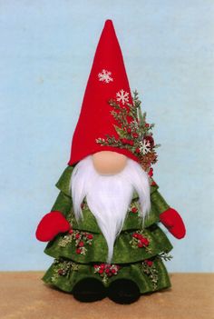 a small christmas tree with a gnome on it's head and snowflakes