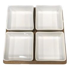 four square white dishes sitting on top of a wooden tray with one empty plate in the middle