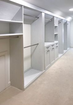 an empty walk - in closet with white cabinets and drawers on the wall, along with carpeted flooring