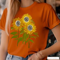 a woman wearing an orange shirt with sunflowers on it