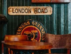 two wooden chairs sitting next to each other in front of a sign that reads london road