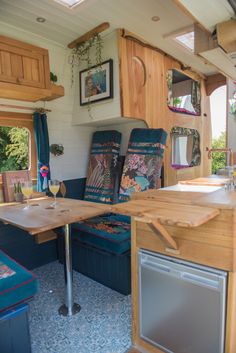 the inside of a small camper with blue couches and wooden tables in it