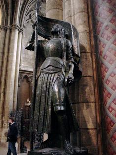 a large bronze statue in the middle of a building next to a tall stone pillar