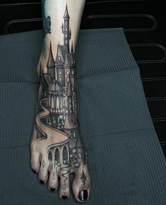 a person's foot with a castle tattoo on it