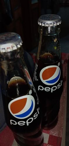 two pepsi soda bottles sitting on top of a table