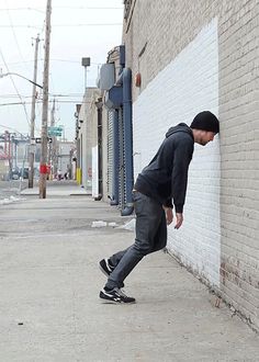 a man leaning against a brick wall on his skateboard