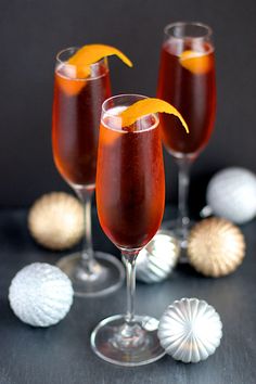 two glasses filled with red wine and garnished with an orange peel