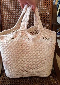 a person is holding a crocheted bag on a chair