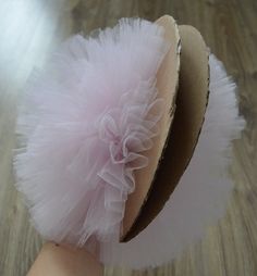 a person's hand wearing a hat with a pink tulle on the top