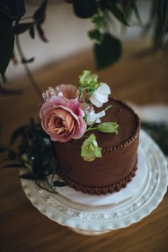 there is a chocolate cake with flowers on the top and bottom layer, sitting on a plate