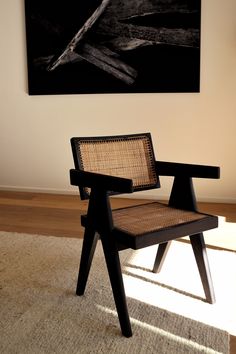 a chair sitting on top of a rug in front of a wall with a painting