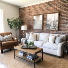 a living room with two couches and a coffee table in front of a brick wall