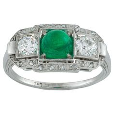 An Art Deco cabochon emerald and diamond ring, the central cabochon cut emerald estimated to weigh 1.1 carats accompanied by GCS Report stating that is of Colombian origin, flanked by two old brilliant-cut diamonds, surrounded by a row of small rose cut diamonds with a daylight in between estimated to weigh a total of 0.75 carats, all claw and millegrain set in a white gold mount with line engraved tapering shoulders, circa 1930, head measuring 1x1.8cm, finger size M, gross weight 3.5 grams. Thi Antique Cocktail Ring, Tsavorite Ring, Emerald Cabochon, Art Deco Emerald, Emerald And Diamond Ring, Art Deco Engagement, Cabochon Ring, Small Rose, Deco Engagement Ring