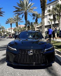 a black sports car is parked on the side of the road in front of palm trees