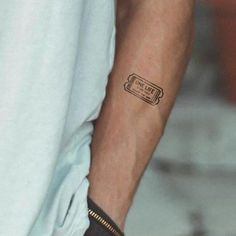 a man's arm with a small ticket tattoo on the left side of his arm