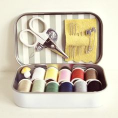 a tin filled with lots of different types of thread and scissors next to each other