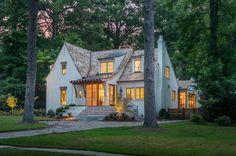 a white house with lots of windows and trees in the front yard at night time