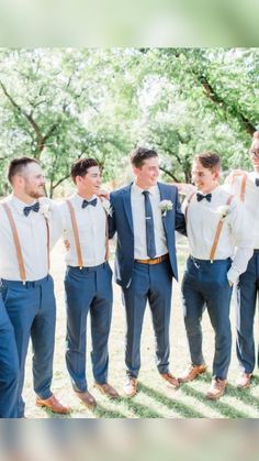 a group of young men standing next to each other in front of trees and grass