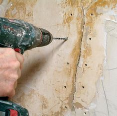 a person using a drill to fix a wall