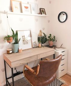 a desk with a chair, potted plants and pictures on the wall above it