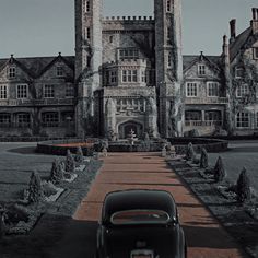 an old car is parked in front of a large building with two towers on each side